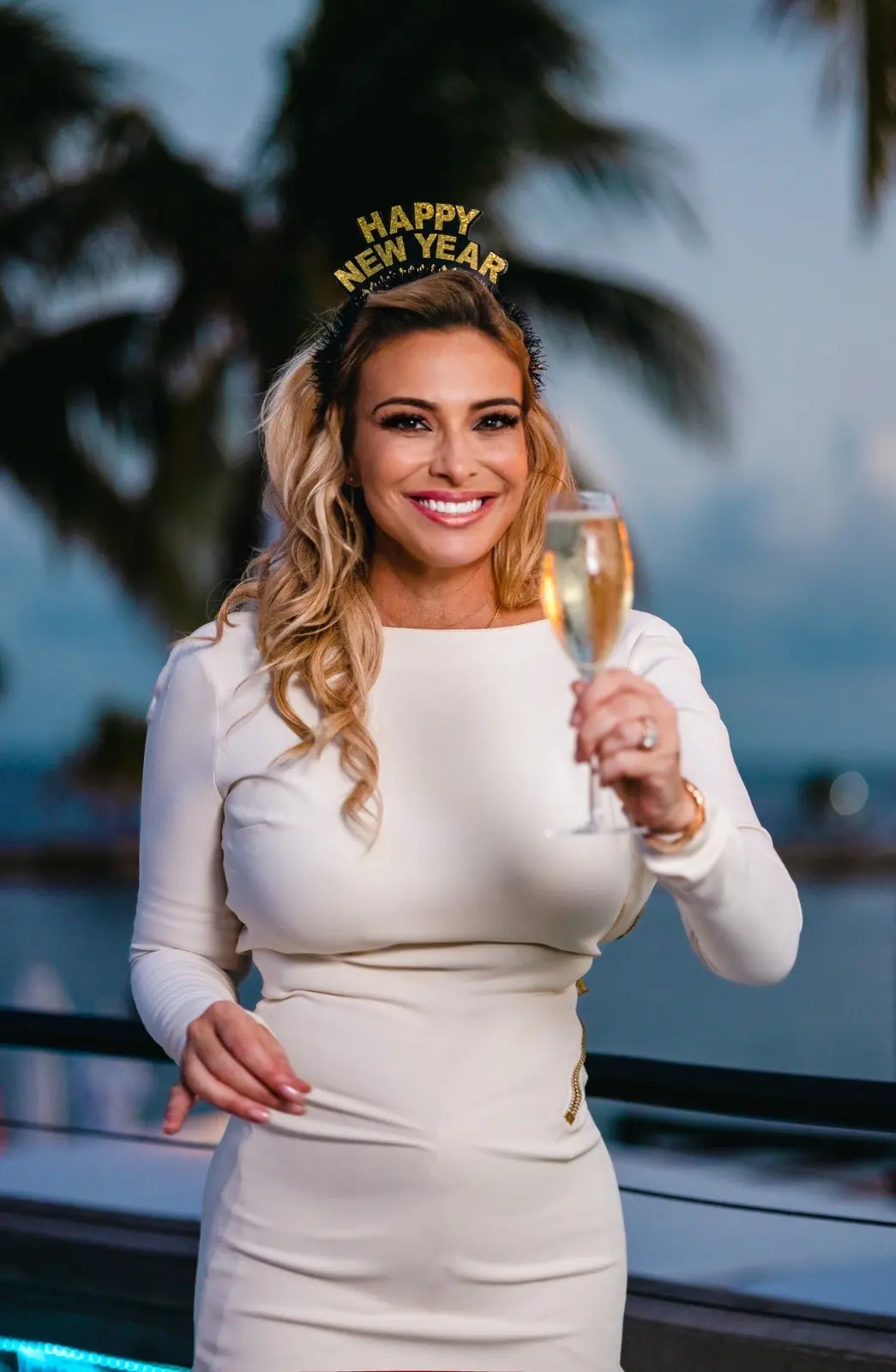 Donatella Arpaia in white on New Year’s Eve, a Happy New Year tiara and a glass of champagne