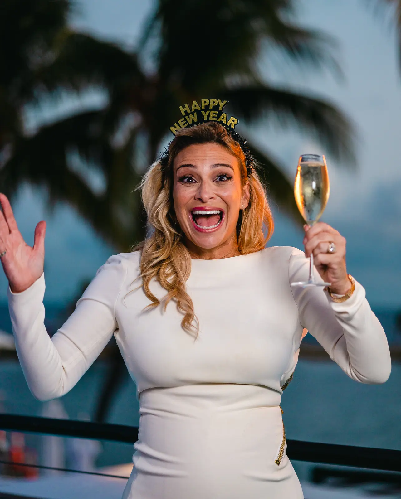 Donatella Arpaia in white on New Year’s Eve, a glass of champagne raised