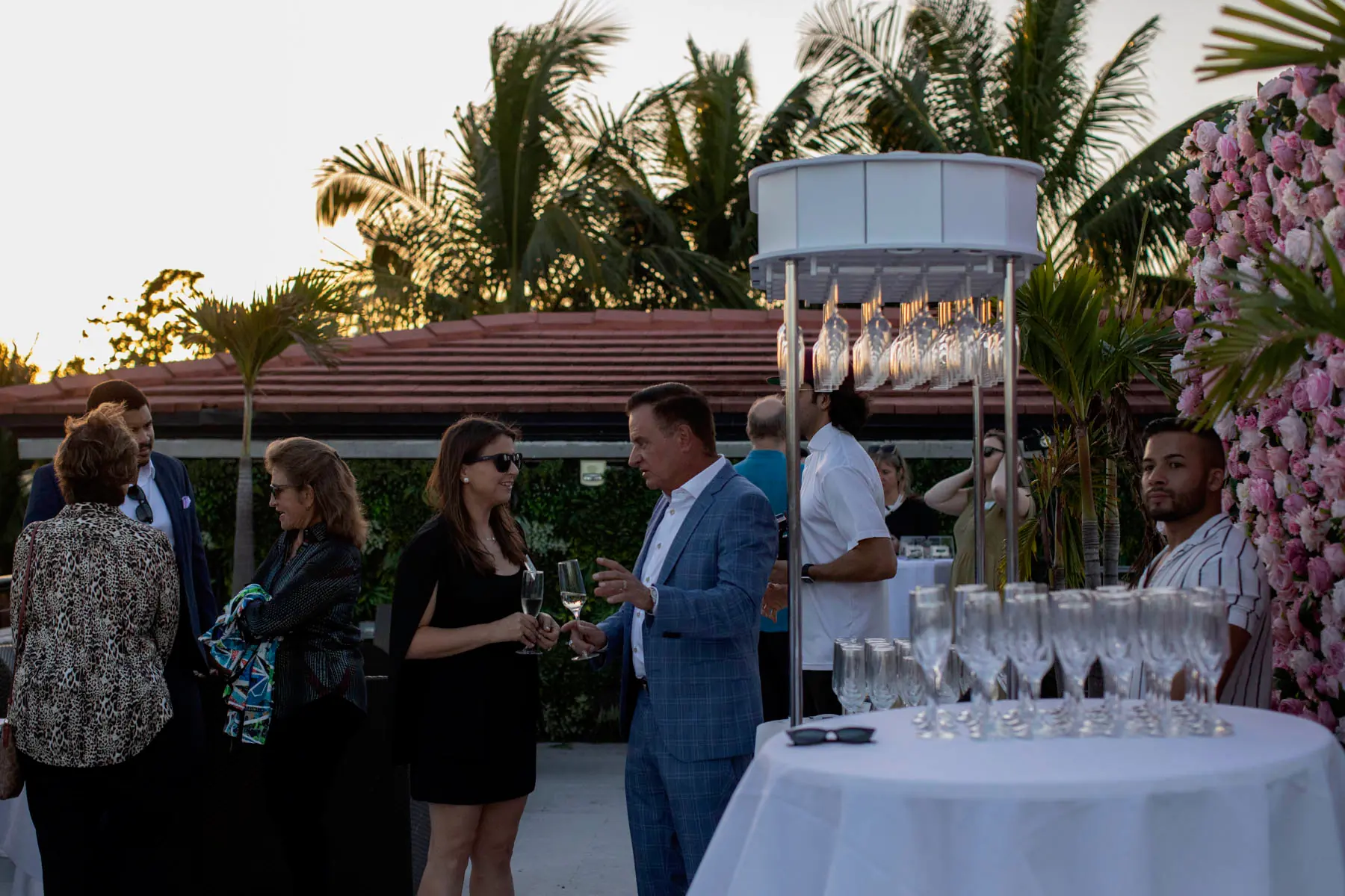 Guests at a cocktail reception on the terrace at sunset, glasses ready on a round table