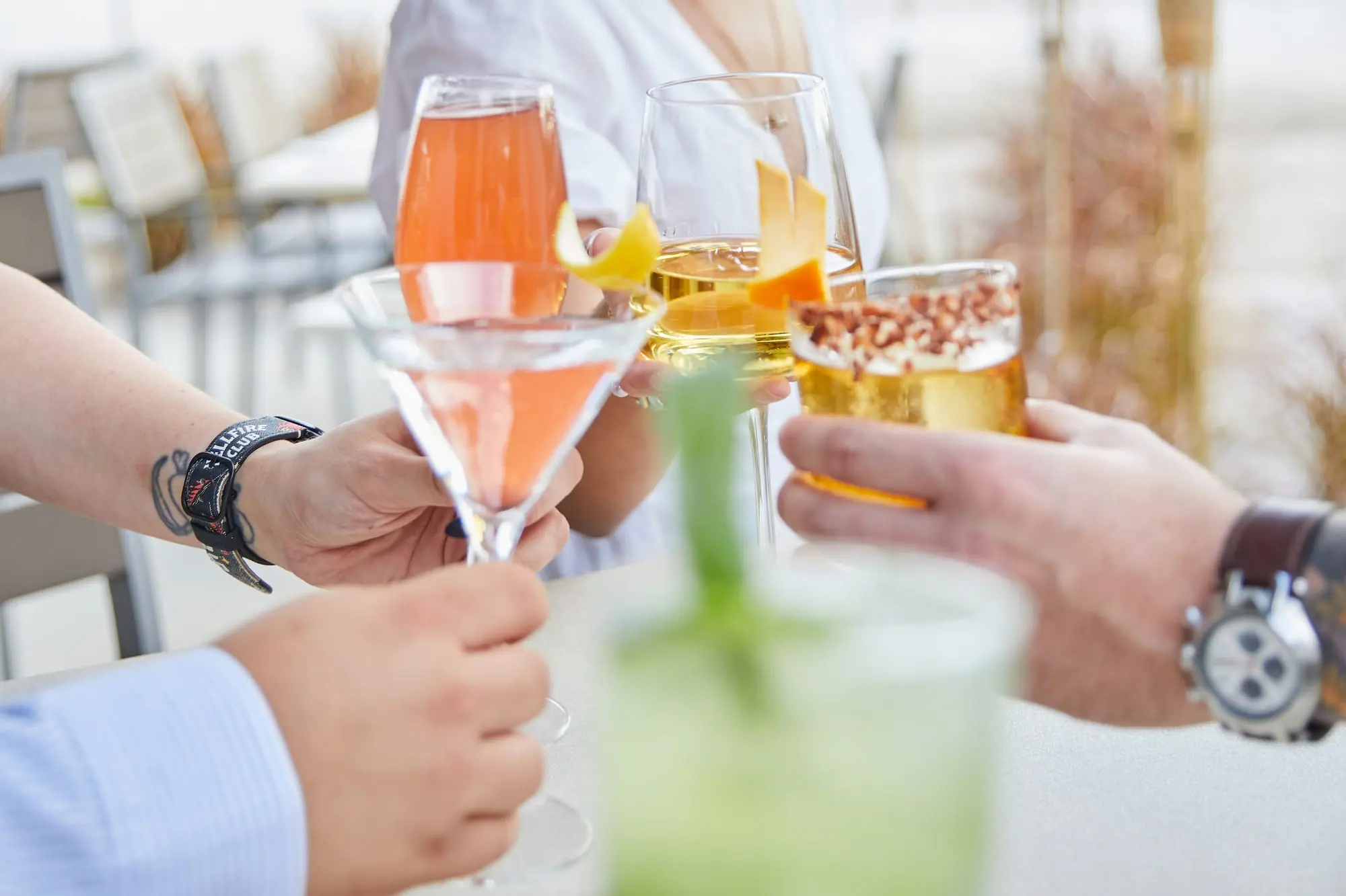 Guests clinking cocktails and a glass of white wine on the patio