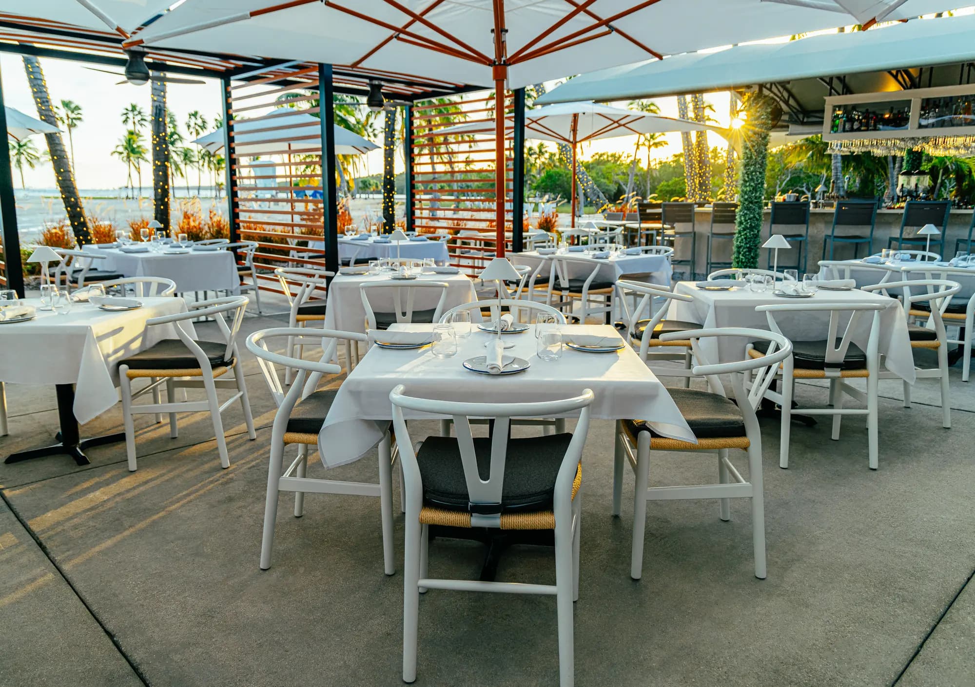 The patio under white umbrellas, set for lunch