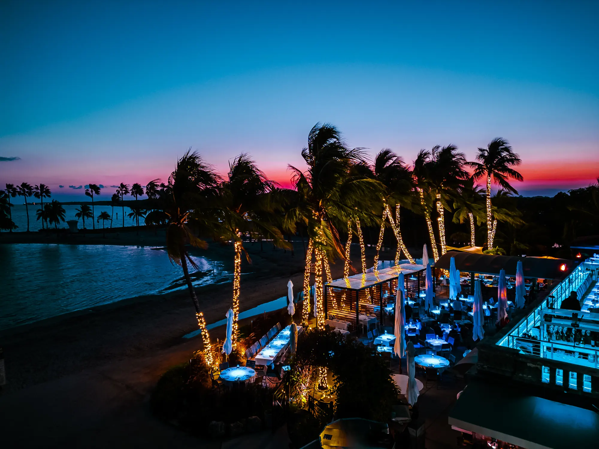 The sky going red over the lagoon, the lit palms and the tables below